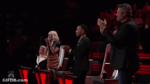 A Group Of People Are Sitting In A Stadium Applauding A Performance . GIF