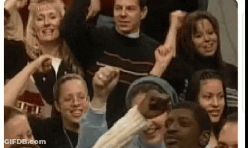 A Group Of People Are Sitting In A Stadium Holding Their Fists In The Air . GIF