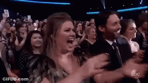 A Group Of People Are Sitting In A Stadium Watching A Concert And Applauding . GIF