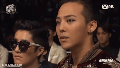 A Group Of People Are Sitting In A Stadium Watching A Concert . GIF