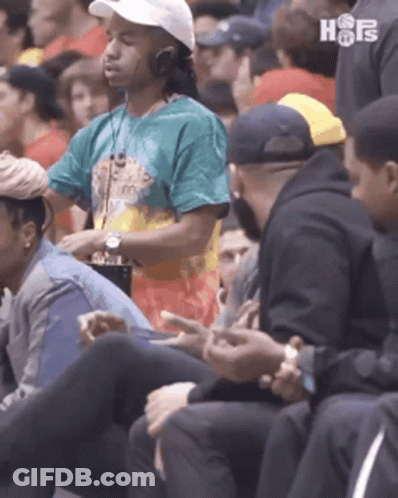 A Group Of People Are Sitting In A Stadium Watching A Game . GIF