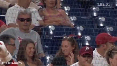A Group Of People Are Sitting In A Stadium Watching A Game . GIF