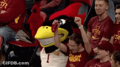 A Group Of People Are Sitting In A Stadium With A Mascot Wearing A Number 1 Shirt GIF
