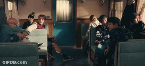 A Group Of People Are Sitting In A Train Car Talking To Each Other . GIF