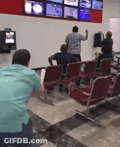A Group Of People Are Sitting In A Waiting Room With A Tv On The Wall GIF