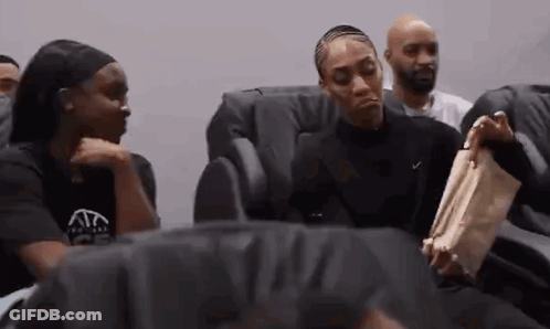 A Group Of People Are Sitting In Chairs Talking To Each Other . GIF