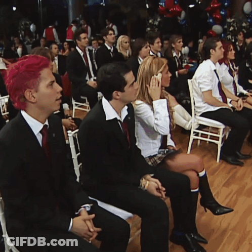 A Group Of People Are Sitting In Chairs Watching A Presentation GIF