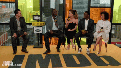 A Group Of People Are Sitting In Front Of A Sign That Says Imdb GIF