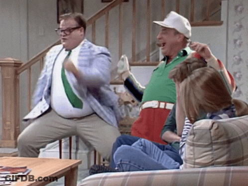 A Group Of People Are Sitting On A Couch And One Man Is Standing On A Chair GIF