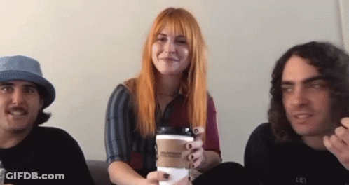 A Group Of People Are Sitting On A Couch And One Of Them Is Holding A Coffee Cup . GIF