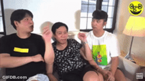 A Group Of People Are Sitting On A Couch Talking To Each Other In A Living Room . GIF