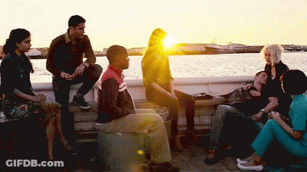 A Group Of People Are Sitting On A Dock Near A Body Of Water GIF