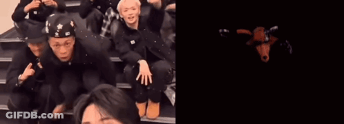 A Group Of People Are Sitting On A Set Of Stairs Next To A Red Monster With The Number 10 On Its Face GIF