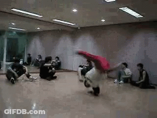 A Group Of People Are Sitting On The Floor In A Dance Studio Watching A Person Do A Trick . GIF