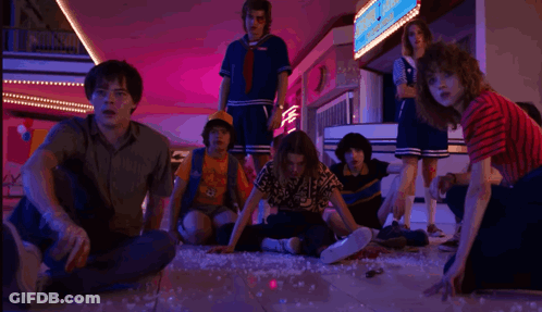 A Group Of People Are Sitting On The Floor In A Mall Looking At Something . GIF
