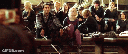 A Group Of People Are Sitting On The Steps Of A Building And One Of Them Is Holding A Sword GIF