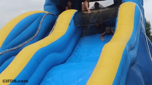 A Group Of People Are Sliding Down A Blue And Yellow Inflatable Water Slide . GIF
