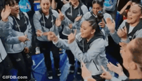 A Group Of People Are Standing Around A Basketball Court Giving High Fives . GIF