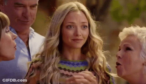 A Group Of People Are Standing Around A Blonde Woman Who Is Crying . GIF
