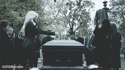 A Group Of People Are Standing Around A Coffin GIF
