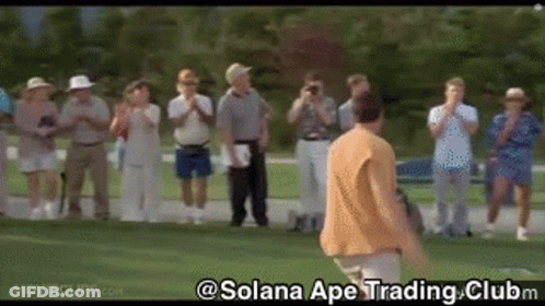 A Group Of People Are Standing Around A Golf Course Watching A Man Swing A Golf Club . GIF