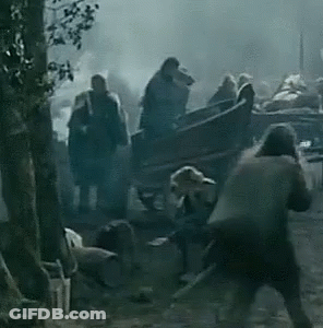 A Group Of People Are Standing Around A Horse Drawn Carriage In The Woods . GIF