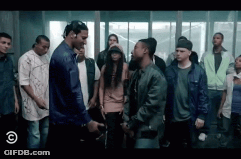 A Group Of People Are Standing Around A Man In A Blue Jacket . GIF