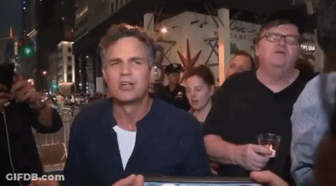 A Group Of People Are Standing Around A Man Wearing Glasses And A Hat That Says ' Abercrombie ' On It GIF