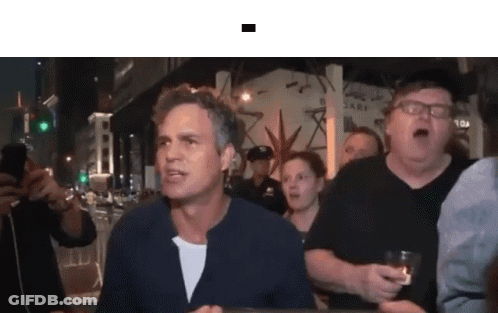 A Group Of People Are Standing Around A Man Who Is Holding A Glass . GIF