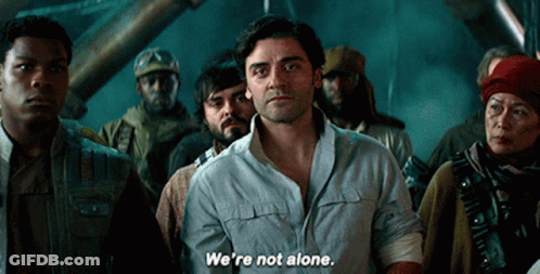 A Group Of People Are Standing Around A Man Who Says " We 'Re Not Alone " GIF
