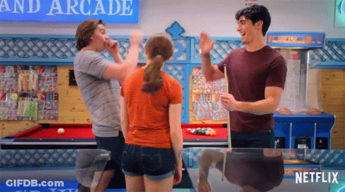 A Group Of People Are Standing Around A Pool Table In An Arcade With A Netflix Logo In The Corner . GIF