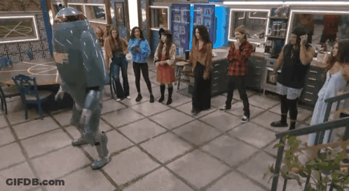 A Group Of People Are Standing Around A Robot Dancing GIF