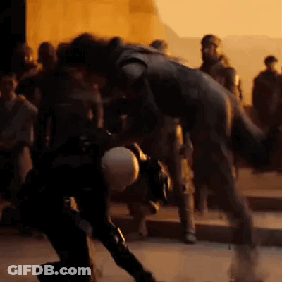 A Group Of People Are Standing Around A Statue Of A Man In A Black Suit . GIF