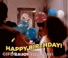 A Group Of People Are Standing Around A Table With Balloons And Saying `` Happy Birthday ! Enjoy Your Day ! `` GIF