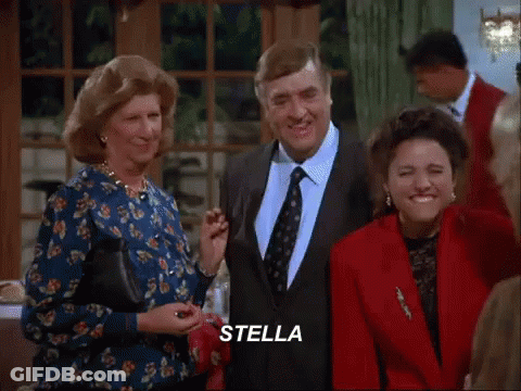 A Group Of People Are Standing Around A Table With The Word Stella Written On The Screen GIF
