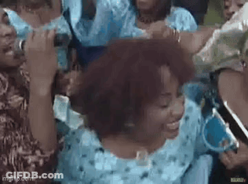 A Group Of People Are Standing Around A Woman In A Blue Dress Holding A Microphone . GIF