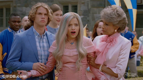 A Group Of People Are Standing Around A Woman In A Pink Dress And A Man In A Blue Suit GIF