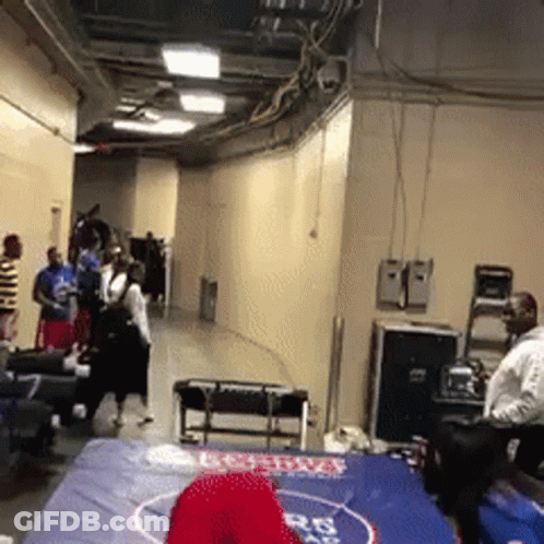 A Group Of People Are Standing Around A Wrestling Mat With A Red Hat On It That Says Boston GIF