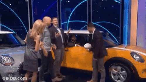 A Group Of People Are Standing Around A Yellow Mini Cooper . GIF