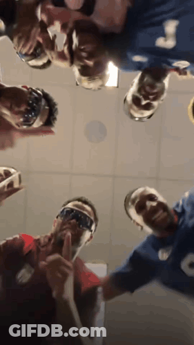 A Group Of People Are Standing In A Circle Looking Up At The Camera . GIF