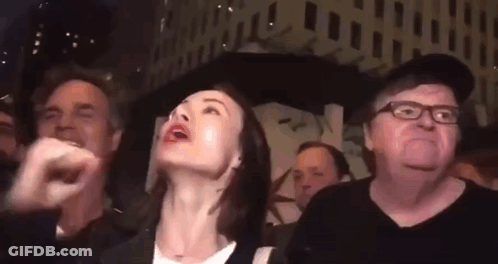 A Group Of People Are Standing In A Crowd And Looking Up At Something . GIF
