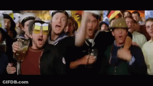 A Group Of People Are Standing In A Crowd Holding Glasses Of Beer And Wearing Helmets . GIF