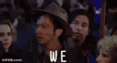 A Group Of People Are Standing In A Crowd With The Words `` Again '' Written On The Bottom . GIF