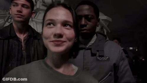 A Group Of People Are Standing In A Dark Room And One Of Them Has A Badge That Says ' A ' GIF