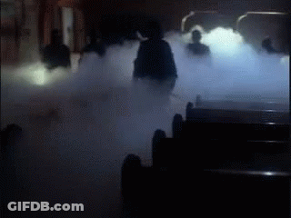 A Group Of People Are Standing In A Dark Room Surrounded By Smoke . GIF