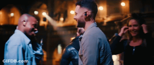 A Group Of People Are Standing In A Dark Room Talking GIF