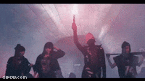 A Group Of People Are Standing In A Dark Room With A Man Holding A Red Flare . GIF
