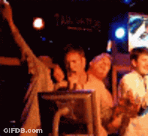 A Group Of People Are Standing In A Dark Room With A Sign That Says Tailgate GIF