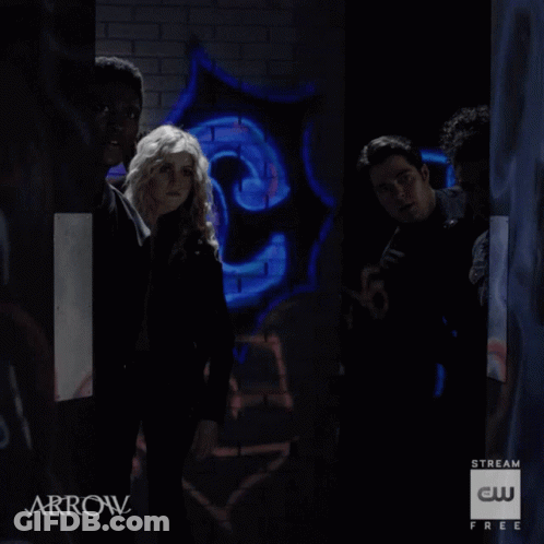 A Group Of People Are Standing In A Dark Room With Arrow Written On The Bottom GIF