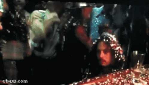 A Group Of People Are Standing In A Dark Room With Confetti Falling On Them GIF